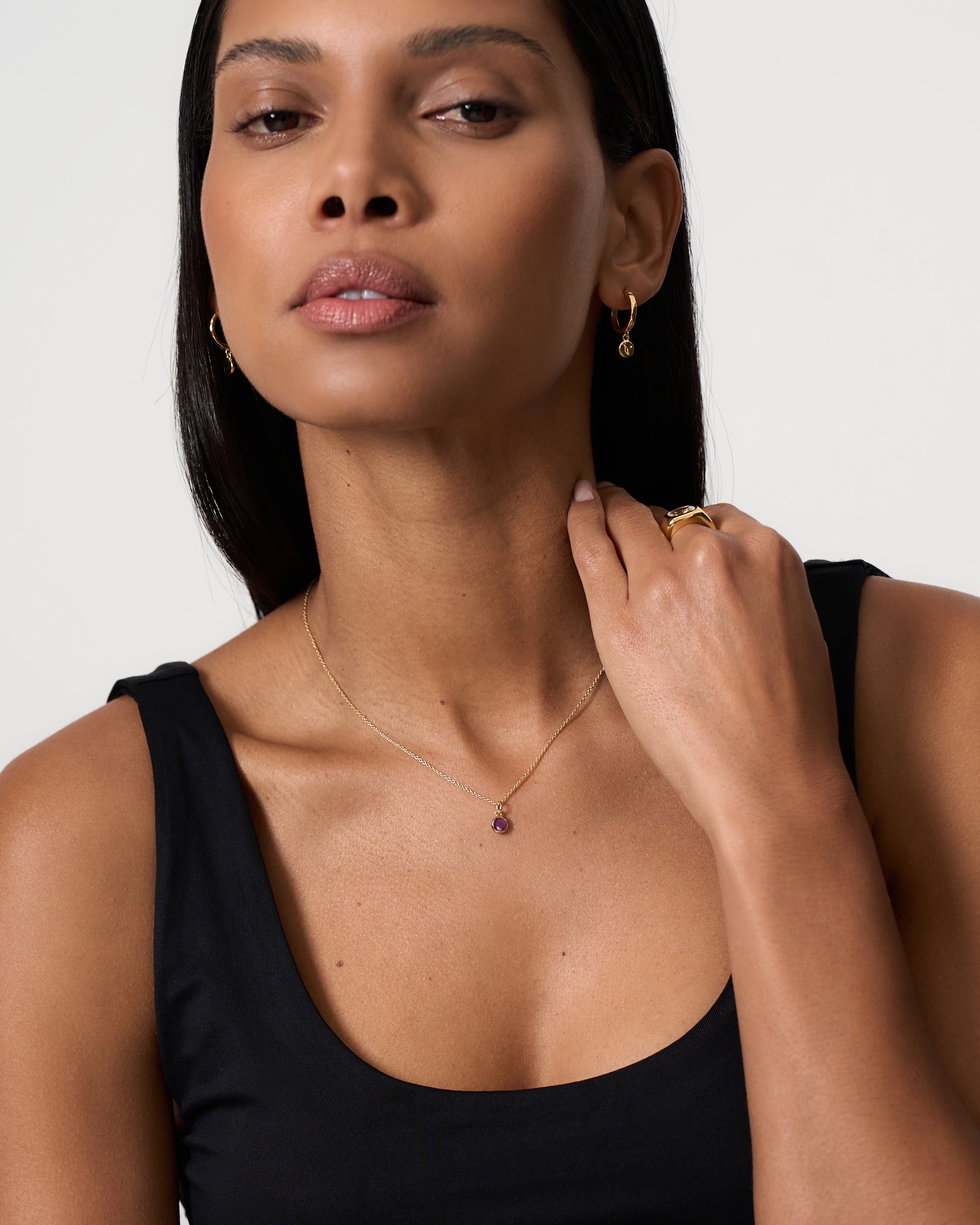 Model is wearing a January round cut garnet and gold vermeil birthstone pendant by Azora.