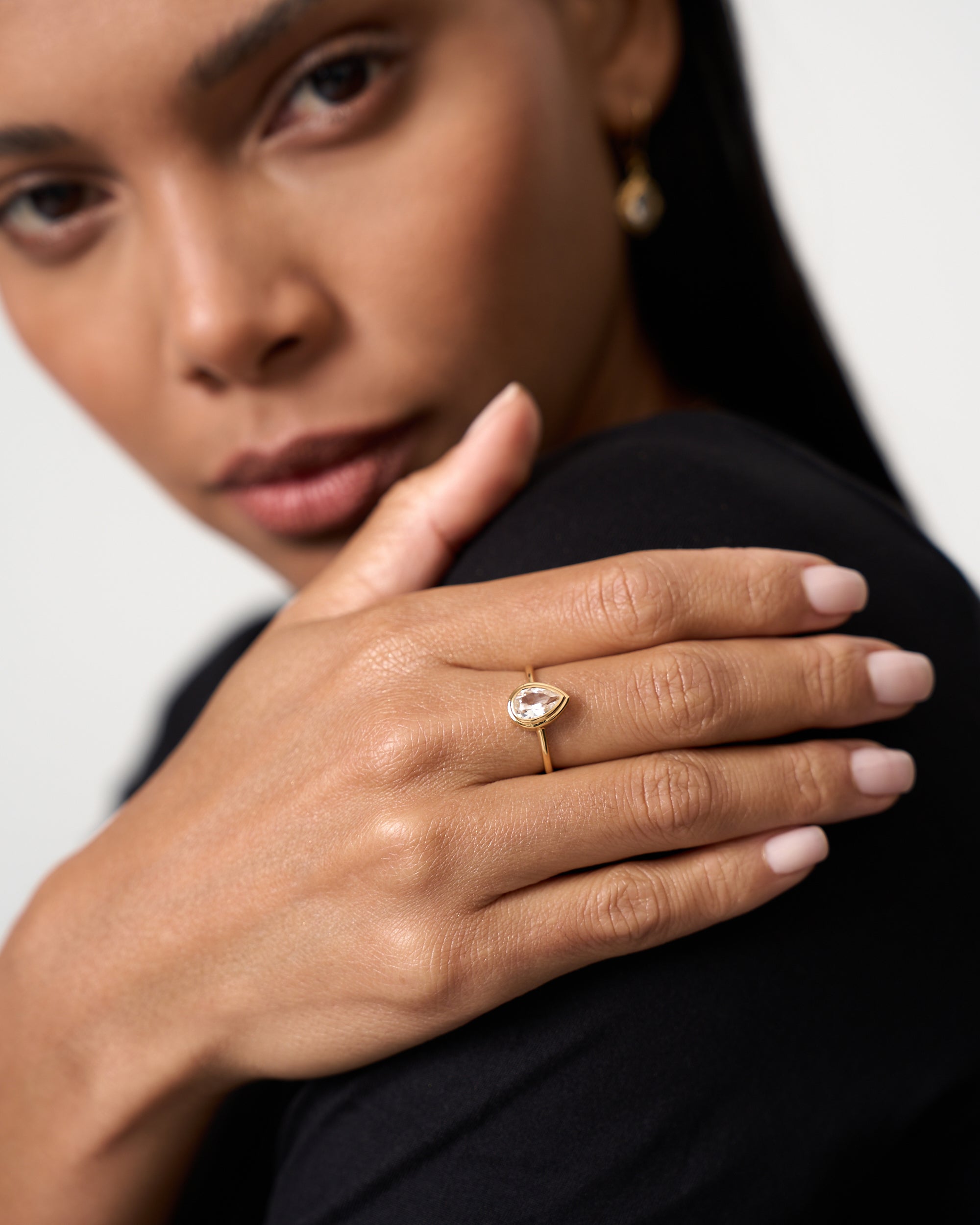 Model wears a pear cut white sapphire gold vermeil ring by Azora Jewellery