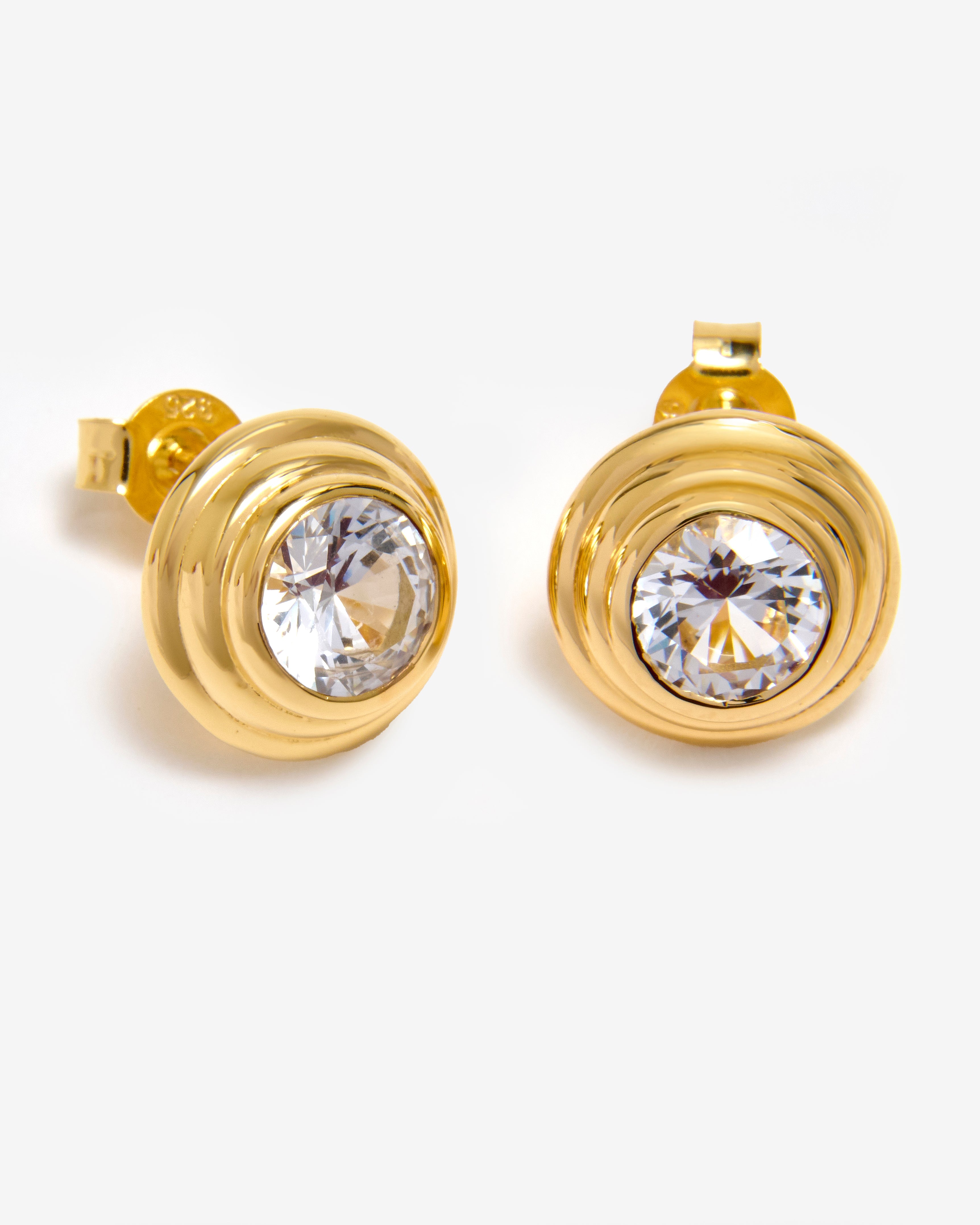 A pair of gold vermeil stud earrings featuring a white sapphire in a solarium setting.