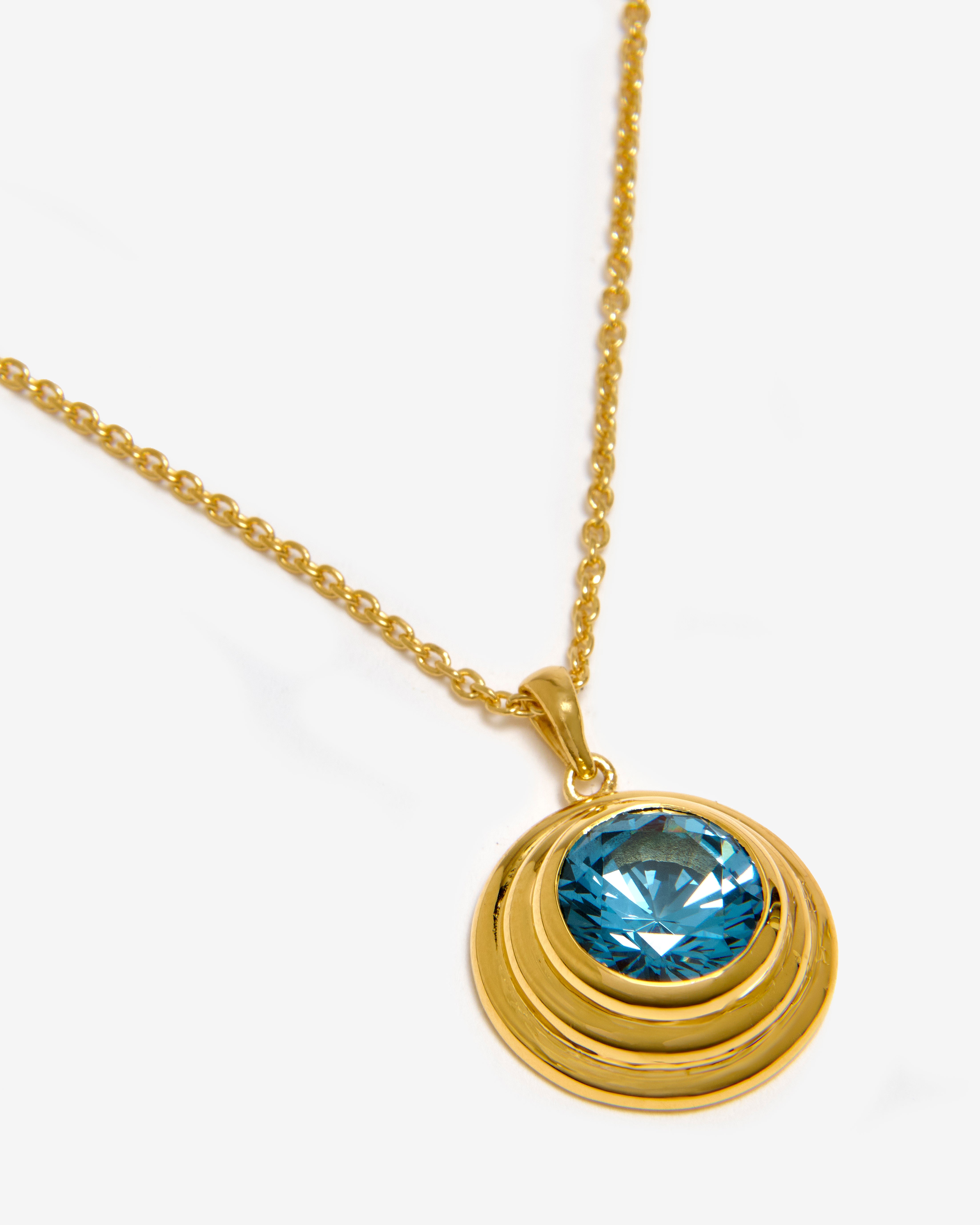 A vermeil solarium pendant necklace featuring a round aquamarine gemstone.
