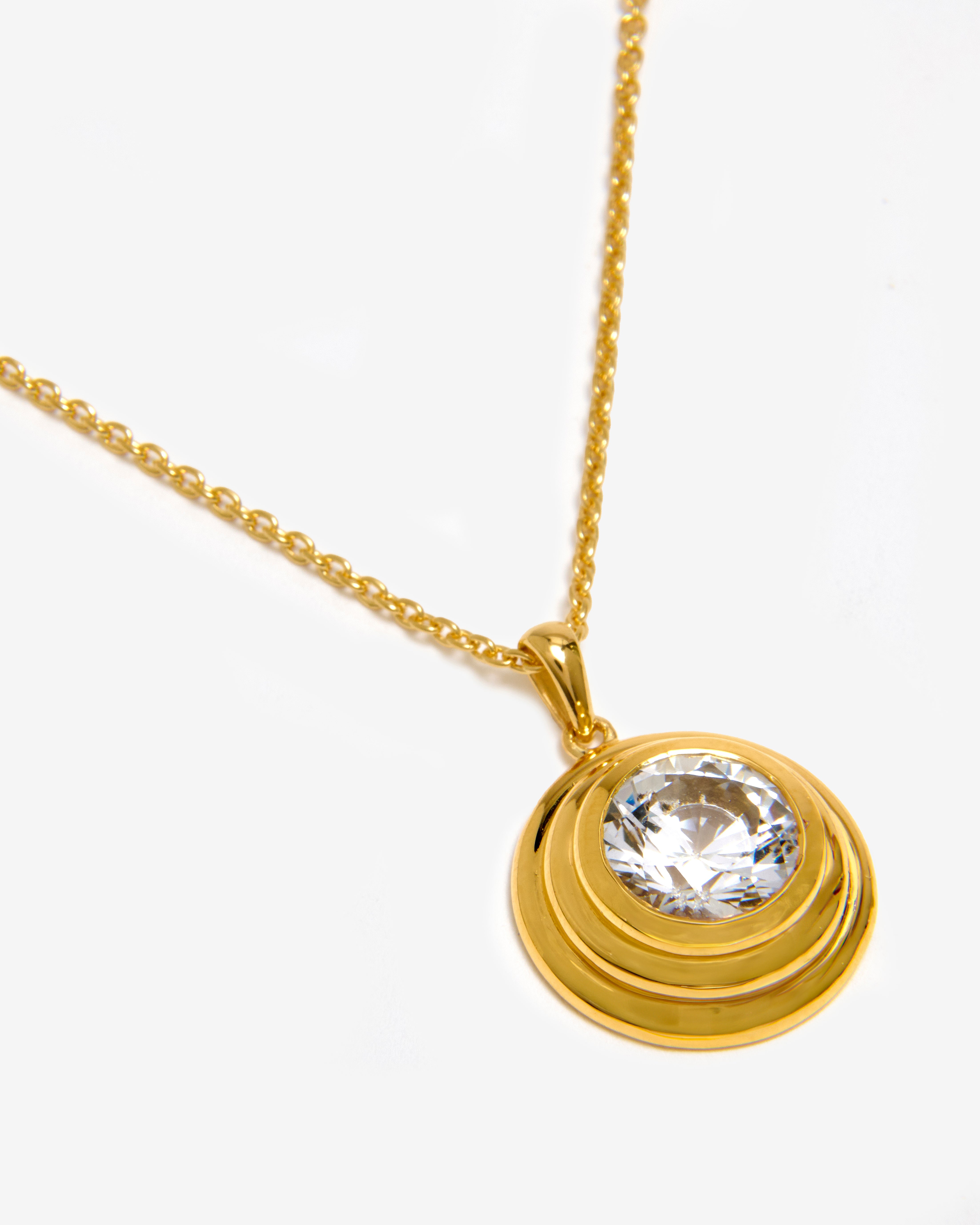 A vermeil solarium pendant necklace featuring a round white sapphire.