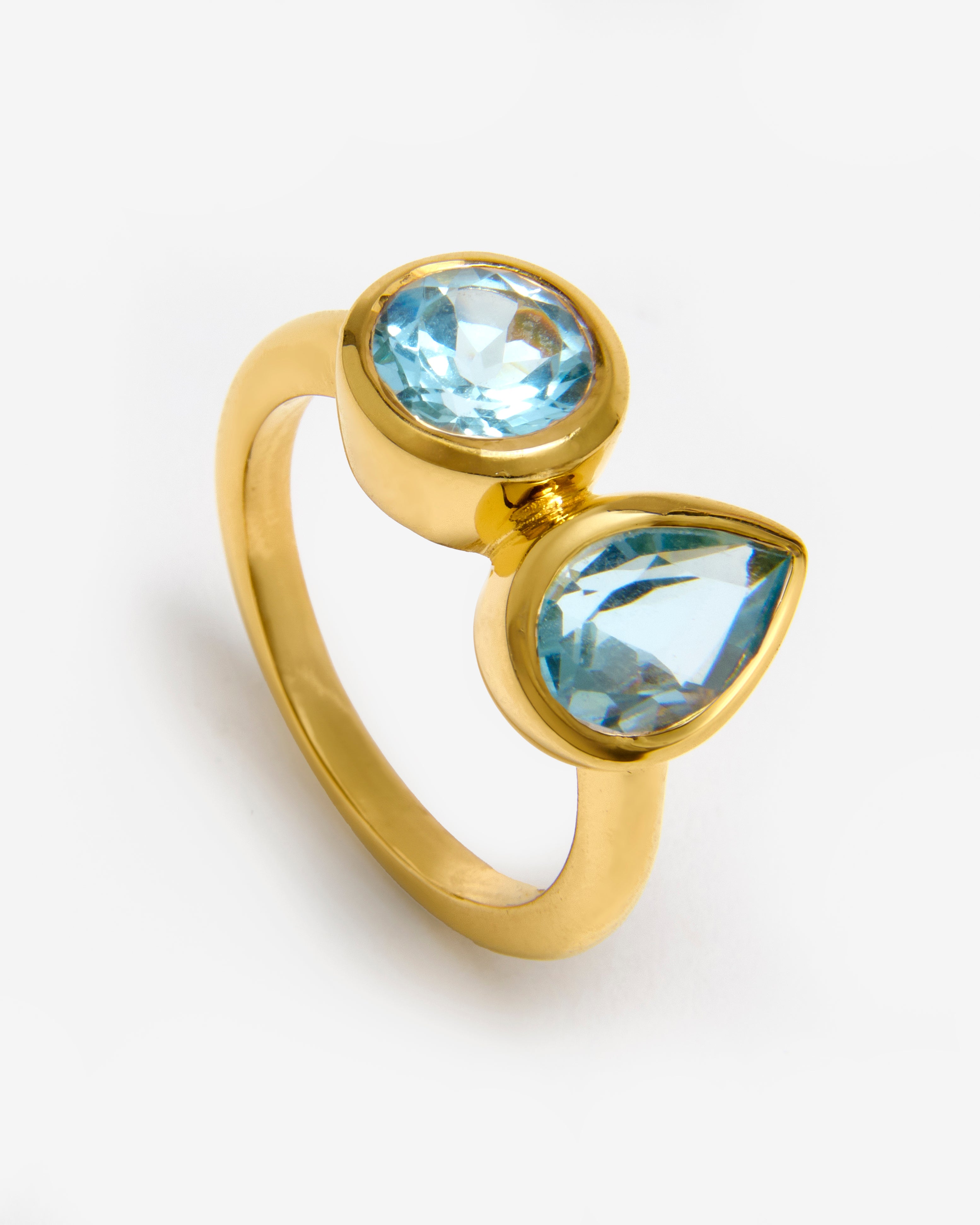 A gold vermeil band ring with two sky blue topaz gemstones set on it.